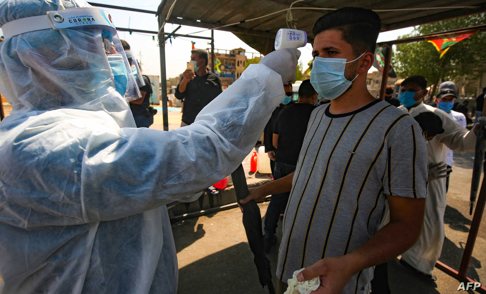 A health worker checks the temperature of a supporter of Shiite cleric Moqtada al-Sadr with disinfectant, as he arrives to take part in the Friday prayers in Sadr City, east of the Iraqi capital Baghdad, on September 11, 2020, amid the novel coronavirus pandemic. (Photo by AHMAD AL-RUBAYE / AFP)