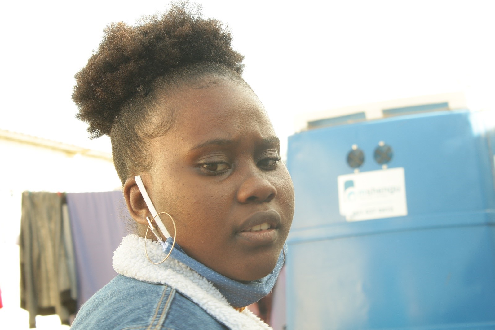 Film director, Mona-Lisa Nsima, standing in front of a portable toilet in Khayelitsha [Gilroy Rinkwest]