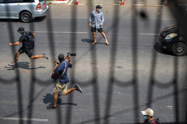 Pro-democracy protesters and a journalist run as riot police officers advance on them during a rally against the military coup in Yangon, Myanmar, on February 27, 2021 [Reuters]