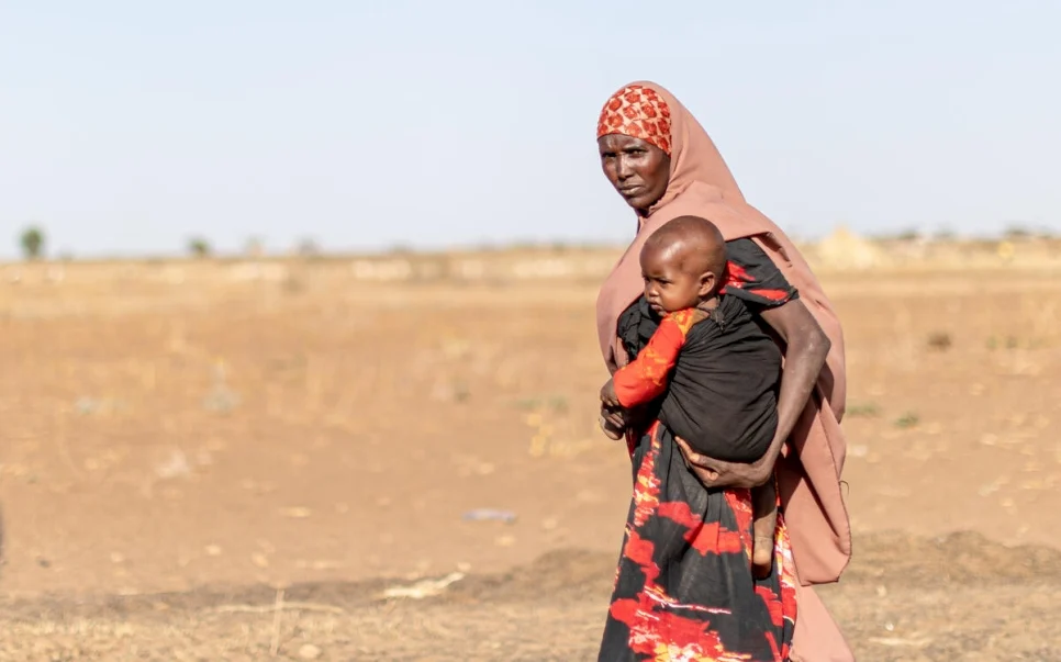 A mother carries her child through the parched landscape of Ethiopia’s Somali region, where thousands of families have been displaced during a recent drought.  © UNHCR/Eugene Sibomana.