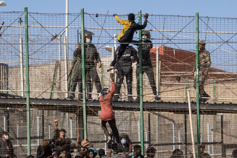 Migrants climb the fences separating the Spanish enclave of Melilla from Morocco on June 24, 2022/Javier Bernardo/AP.