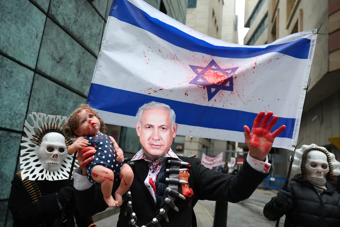 A person wearing a mask depicting Israeli Prime Minister Benjamin Netanyahu holds a doll as people take part in a protest in London, UK, to mark 100 days since the start of the war on Gaza [Toby Melville/Reuters]