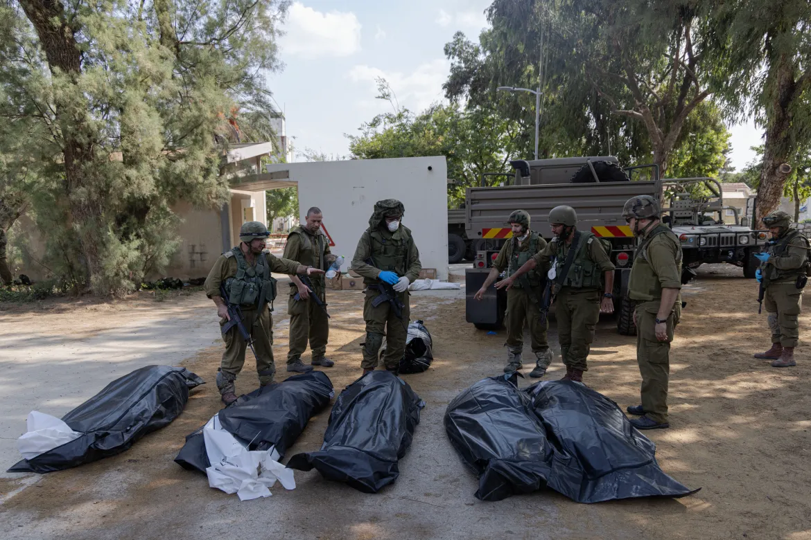 Israeli soldiers stand next to the bodies of Israelis killed by Hamas fighters in kibbutz Kfar Aza. [Faiz Abu Rmeleh/Al Jazeera]