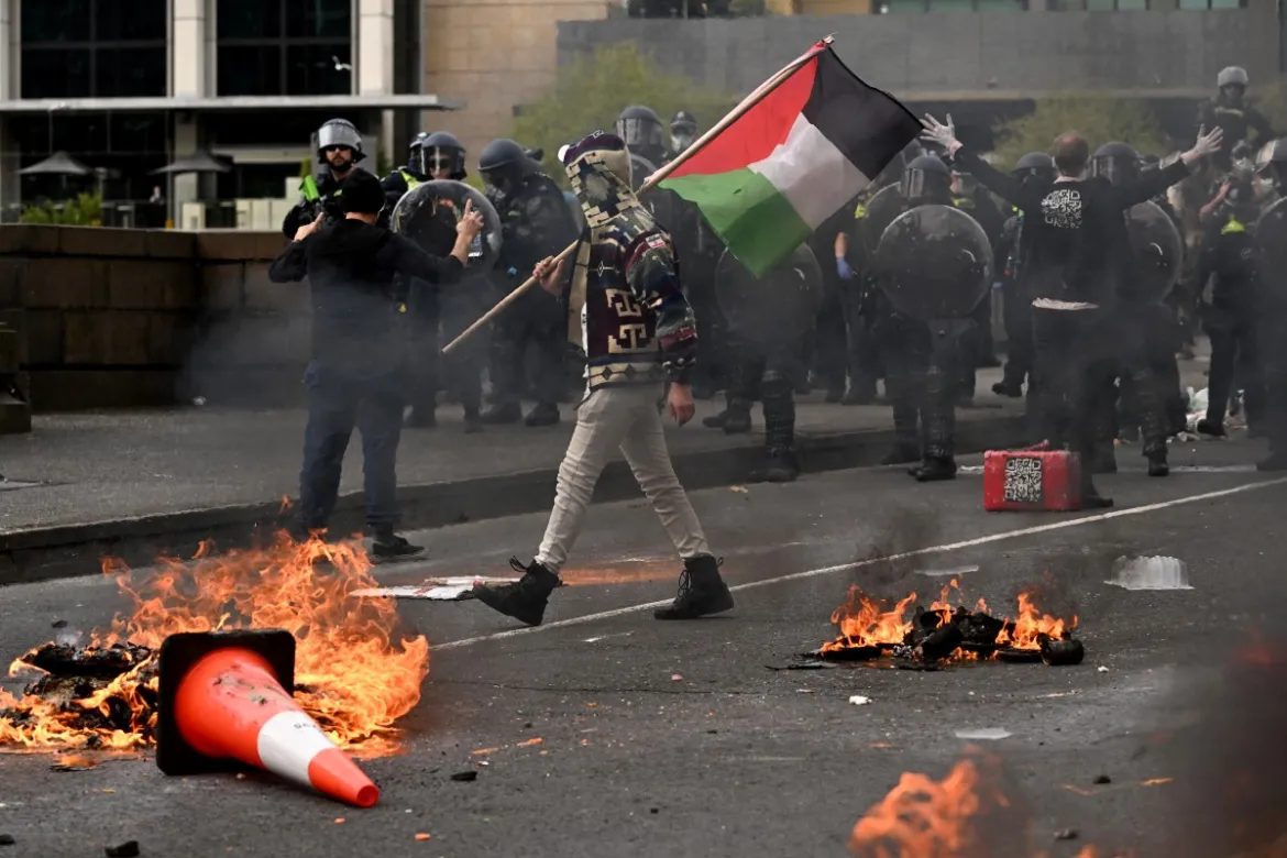 Archive/A man waves a Palestinian flag as protesters confront police outside the Land Forces 2024 arms fair in Melbourne. [William West/AFP]