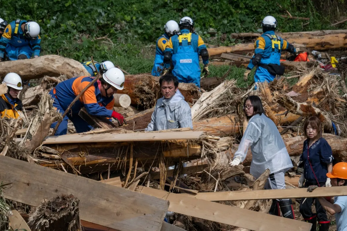 A father (C) searches for his missing 14-year-old daughter among debris washed away from flooding along the Tsukada River following heavy rain in the city of Wajima, Ishikawa prefecture. [Yuichi Yamazaki/AFP]