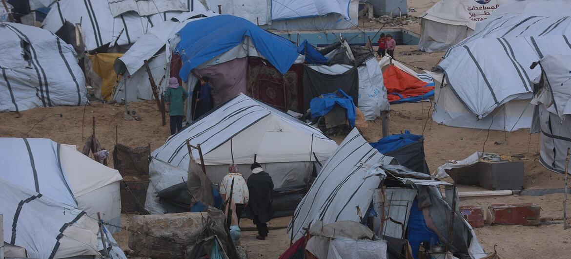 UN News People navigate a makeshift refugee camp in Gaza.
