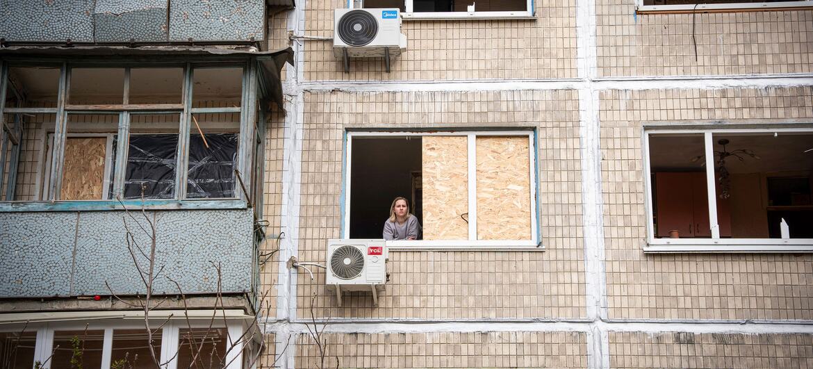 © UNOCHA/UNRCO/Ximena Borrazas A woman looks out from a window of a bombed apartment building in Kyiv, Ukraine.