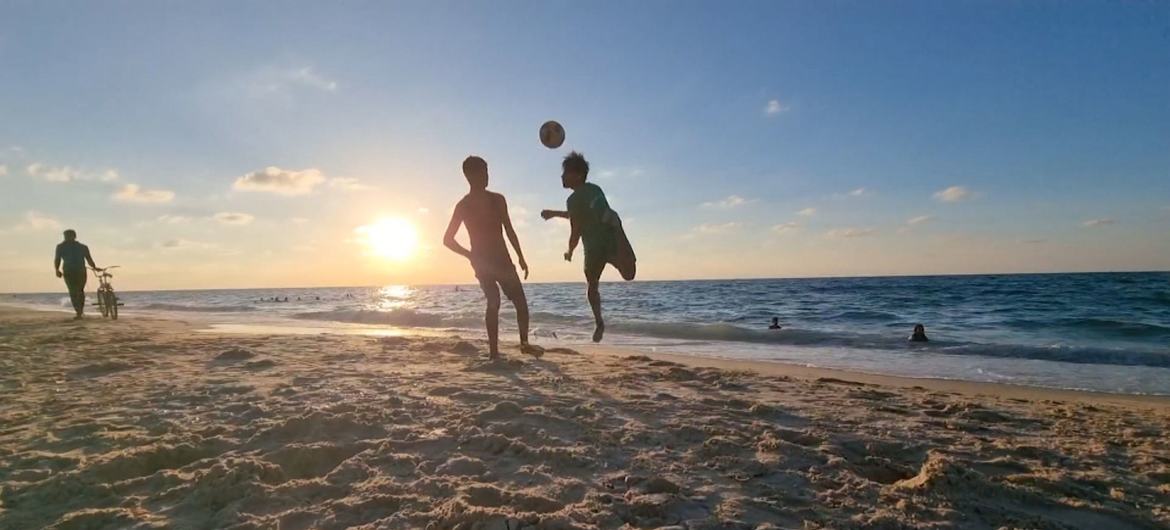 UN News Two football players practice on a beach in Gaza.