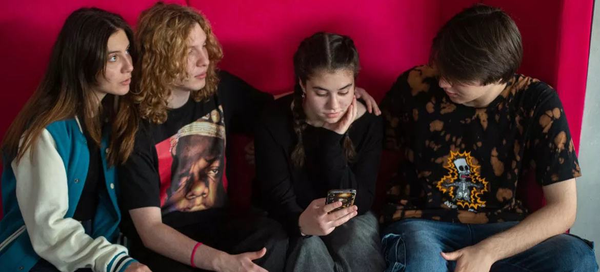 © UNICEF Teenagers watch a mobile phone.
